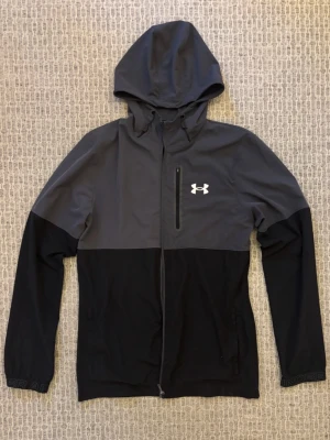 Grå Under Armour windbreaker - Under armour jacka i bra skick förutom att drag kedjan har lossnat, Därav det billiga priset. Så vid köp måste man nog ta den till en skräddare och laga men de går rätt så enkelt och billigt🙌