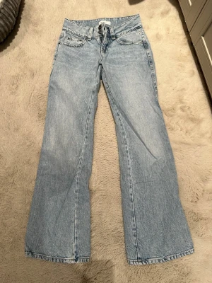 Ljusblå bootcut jeans från Gina Tricot - Snygga ljusblå bootcut jeans från Gina tricot med klassisk femficksdesign och dragkedjegylf samt Y2K style med låg midja. Jeansen har en något utsvängd passform nertill och är tillverkade i denim av bomull. Perfekta för en avslappnad och trendig look. Rensade från garderoben, helt nya och har använt 2 gånger 
