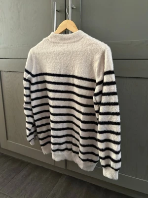 Randig stickad tröja  - Mysig stickad tröja i vitt med horisontella ränder. 