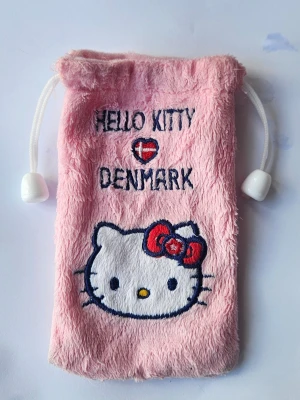 Hello Kitty rosa påse - Supergullig rosa plånbok i mjuk plysch med Hello Kitty-brodyr och texten 'Hello Kitty ♥ Denmark'. Dragskostängning med vita snören och plastdetaljer. Perfekt för småsaker eller mynt. Köpt i Danmark