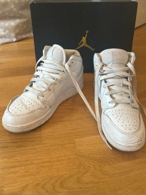 Vita Air Jordan 1 Mid sneakers - Snygga helvita Air Jordan 1 Mid sneakers från Nike, användning syns 
