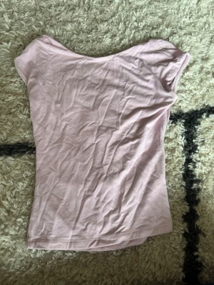 Ljusrosa ärmlös topp - En enkel och stilren ljusrosa topp med ärmlös design. Toppen har en rund halsringning och är gjord i ett mjukt bomullsmaterial som känns skönt mot huden. Perfekt att matcha med jeans eller kjol för en avslappnad look. öppen rygg 