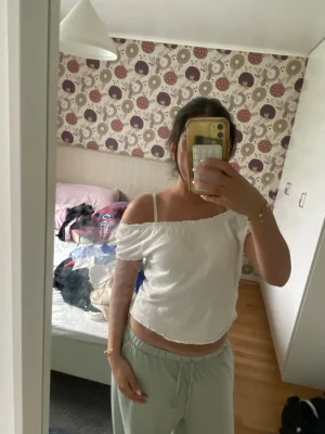 Vit offshoulder topp - Söt vit offshoulder topp med resår och kort ärm. Toppen är croppad och har en smockad struktur som ger en skön passform. Perfekt för varma dagar och enkel att styla med både jeans och kjol.