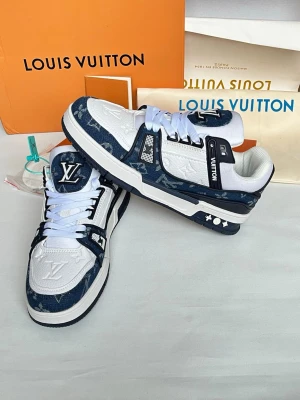 Louis Vuitton blåvita sneakers - Snygga Louis Vuitton sneakers i blått och vitt med klassiskt monogrammönster. Skorna har vita snören, LV-logga på plösen och detaljer i mocka och läder. Sulan är vit med blå inslag och coola stjärndetaljer på sidan. Perfekta för dig som gillar exklusiv streetstyle.