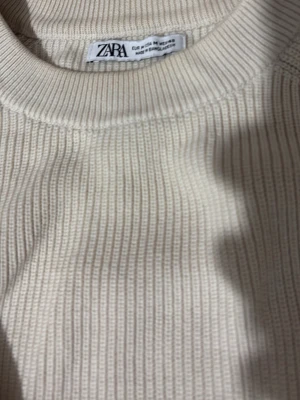 Beige ribbstickad tröja från Zara - Säljer en stilren beige ribbstickad tröja från Zara. Tröjan har rund halsringning, långa ärmar och breda muddar vid ärmslut och nederkant. Perfekt basplagg i garderoben och enkel att matcha med olika outfits.
