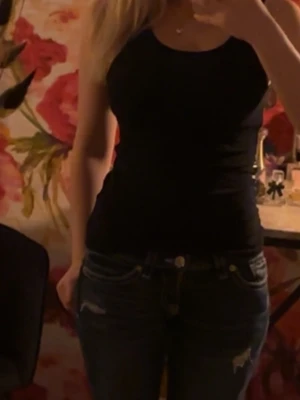 Svart ribbad linnetopp - Säljer en svart ribbad linnetopp med smala axelband. Toppen har en tight passform och är perfekt att styla med jeans eller kjol. Enkel och stilren design som passar till många olika looks.