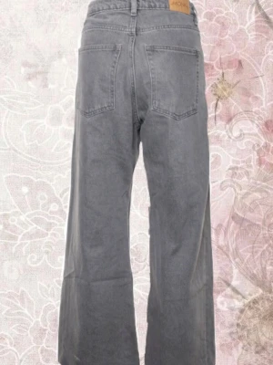 Gråa vida jeans från Monki - Säljer ett par gråa jeans från Monki med hög midja och riktigt breda ben. Jeansen har klassiska bakfickor och är gjorda i mjukt bomullstyg. Perfekta för dig som gillar en avslappnad och trendig look.