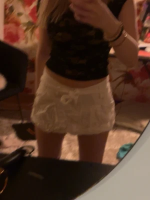 Vita volangshorts med snörning - Säljer ett par vita shorts med volangdetaljer och snörning i midjan. Shortsen har en loose passform och är perfekta för sommaren. De är midwaist och gjorda i ett mjukt bomullsliknande material.