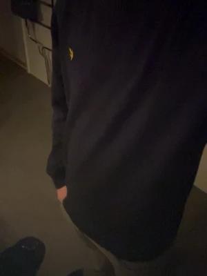 Mörkblå tröja från Lyle & Scott - Mörkblå rundhalsad tröja från Lyle & Scott med den klassiska gula loggan broderad på bröstet. Tröjan har en enkel och stilren design med långa ärmar och ribbade muddar vid ärmslut och nederkant. Perfekt för en clean och avslappnad look., lite för stor men shit snyggg och köp