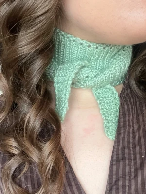Ljusgrön virkad halsduk Sophie scarf - Supersöt ljusgrön virkad halsduk, perfekt att knyta runt halsen för en trendig look. Smal och kort modell som ger en cool touch till outfiten. 93cm.
