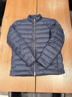 Matinique Lättviktsdunjacka | Blå | Storlek S | Fint skick - :  Beskrivning: Säljer en mycket fin lättviktsjacka från Matinique, inköpt för ca ett år sedan i Köpenhamn. Jackan är i en klassisk mörkblå färg och i ett mycket bra skick då den tagits väl om hand.  Perfekt som en snygg vårjacka eller som ett värmande lager under en rock. Dansk design när den är som bäst – stilren, lätt och funktionell.  Modell: Mapuffy / Lättviktsdun.  Storlek: S (Small).  Skick: Mycket bra/Bra skick. Inga hål
