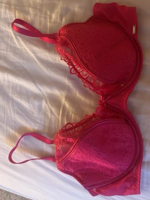 Rosa spets bh - Snygg rosa bh med bygel och vadderade kupor. Bh:n har tunna, justerbara axelband och är dekorerad med vacker spets över hela framsidan. Perfekt för dig som gillar feminina detaljer och en klassisk look.