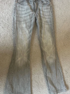 Ljusgrå flared lowwaist jeans - Low waist flared jeans med broderi på bakfickorna. Storlek 158