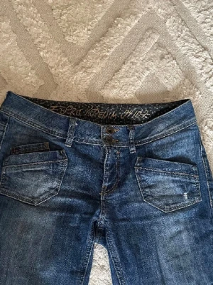 Blå bootcut jeans Esprit Denim - Säljer ett par blå bootcut jeans från Esprit Denim med dubbla knappar i midjan och coola fickdetaljer fram. Jeansen har rå kant nertill och klassisk tvättad look. Perfekta för dig som gillar en avslappnad men snygg stil(bilder från gamla säljaren)