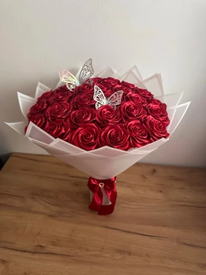 Rosor bukett 30 rosor  - Säljer en bukett med röda konstgjorda rosor i plast, inslagna i vitt papper och dekorerad med två silvriga fjärilar i metall. Buketten är bunden med ett rött sidenband och har en elegant, rund form. Perfekt som dekoration eller present.