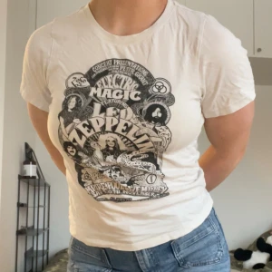 Vit Led Zeppelin t-shirt - Säljer en vit t-shirt med coolt Led Zeppelin-tryck framtill. T-shirten har korta ärmar och rund hals. Perfekt för dig som gillar bandtröjor och vill ha en avslappnad stil. Står XS i tröjan, men jag har generellt M och anser att den passar mig ändå, bara inte min stil längre