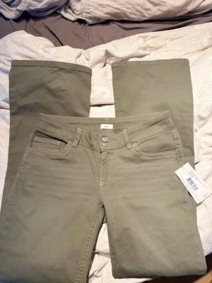 Lågmidjade jeans  - Snygga gröna  jeans från Nelly med utsvängda ben och klassisk femficksdesign. Jeansen har låg midja, dekorativa sömmar på bakfickorna. Tillverkade i ett mjukt bomullsmaterial med lite stretch för extra komfort.