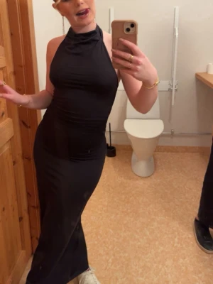 Svart lång halterneckklänning - Säljer en svart långklänning med halterneck och figurnära passform. Klänningen är ärmlös och har en elegant, slät design som framhäver siluetten. Perfekt för dig som vill ha en stilren och tidlös look Är ifrån Gina Tricot i storlek S, använd en gång så är som ny💕.