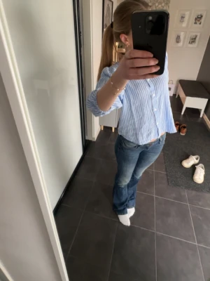 Blåvit randig blus med puffärm - Snygg blus i blått med vita ränder och puffiga långärmar. Blusen har rund halsringning och knäppning framtill med små vita knappar. Tillverkad i ett lätt och luftigt tyg som känns fräscht och somrigt.