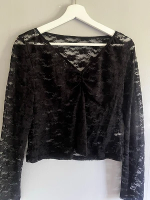 Shein Svart spetsblus med v-ringning - Säljer en svart, transparent spetsblus med v-ringning och långa ärmar. Blusen har ett feminint och trendigt utseende med blommigt spetsmönster och är lätt croppad. Perfekt att styla över ett linne eller bralette för en cool look. Den är liten i storleken skulle säga att den är en M. 