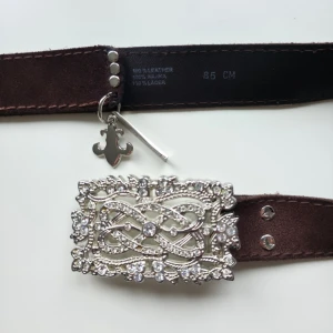 Brunt skärp med strass - Supersnyggt brunt vintage (2000-tal) skärp i läder med ett silverspänne dekorerat med strass stenar. 💕 Jättebra skick, två strass saknas men det syns inte alls. 