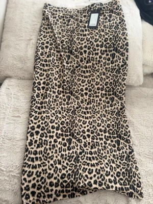 Långkjol med leopardmönster(ordinarie pris: 150) - Säljer en snygg långkjol med leopardmönster(glamourrr😍) i beige och svart. Kjolen har rak passform och är perfekt för dig som vill sticka ut med ett trendigt djurmönster. Materialet känns mjukt och följsamt mot kroppen.