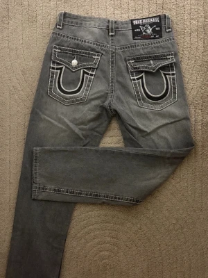 True religion jeans storlek 32 - Ett par äkta True religion jeans i storlek 32 (Byxorna passar även folk med storlek M/L)  Ena fickan har jag råkat tappa knappen på (därav priset) annars är dem helt skavank fria! Hör av er vid frågor eller om ni vill ha fler bilder :)