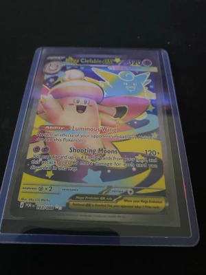 Pokémonkort Mega Clefable GX - Säljer ett Pokémonkort med motivet Mega Clefable GX. Kortet har färgglad design med holografiska detaljer och är skyddat i plastficka. Text och effekter på engelska, perfekt för samlare eller Pokémonfans.