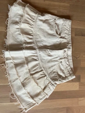 Vit volangkjol i denim - Säljer denna såå fina jeanskjolen från Gina som inte säljs längre. Den har asymmetriska volanger med råa kanter, i väldigt fint skick då den knappt använts. Perfekt nu till sommaren! 😊🧘‍♀️💕Tveka inte att höra av dig vid frågor!