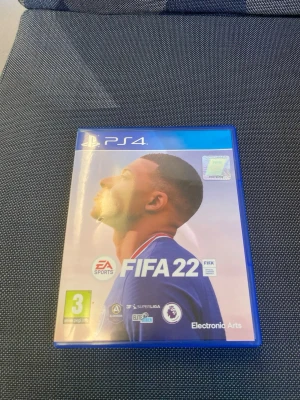 FIFA 22 till PS4 - Säljer FIFA 22 till PlayStation 4. Spelet kommer i ett blått plastfodral med omslag och skiva. Omslaget har en bild på en fotbollsspelare och spelet är från EA Sports. Perfekt för dig som gillar fotbollsspel och vill utmana vänner.