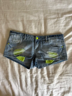 Blå jeansshorts med neon-detaljer - Snygga jeansshorts, säljer då de tyvärr inte passar💕 Midjemått: 39cm