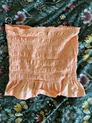 Persikofärgad smockad tubtopp Gina Tricot - Supersöt persikofärgad tubtopp från Gina Tricot med smockad resår över 🧡 Perfekt till jeans eller kjol!😚 Aldrig använd!!