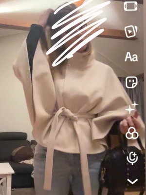 Beige Poncho-kappa - Säljer den snygga beigea poncho-kappan från Nelly💗 One Size, guld detalj och använd 1-2 ggr!! Säljer då jag har en svart som används mer💗