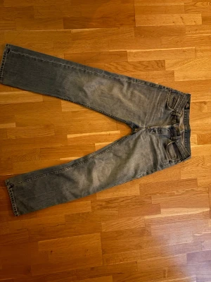 Blå jeans från Lee - Säljer ett par klassiska blå jeans från Lee med rak/baggy passform. Jeansen har en snygg tvättad look och Lee-lapp bak i midjan. Perfekta för dig som gillar tidlös denimstil.