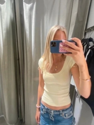 Ljusgul croppad topp med kort ärm - Säljer en ljusgul croppad topp med rund ringning och korta ärmar. Toppen är i mjuk bomull och har en slim passform som sitter snyggt på kroppen. 