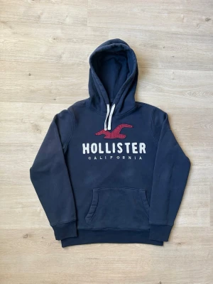 Blå Hollister Hoodie Storlek M - Fin Hollister Hoodie i blå färg. Tröjan är i mycket bra skick och sparsamt använda. |  Äkta som allt annat jag säljer! ✅ |  Storlek: M  | Skick: Mycket Bra Skick - (SE SISTA BILD)| Färg: Blå | Märke: Hollister| Modell: Hoodie |  Hör gärna av dig vid frågor så svarar jag så fort jag kan! 😁|   (SKU - 64)