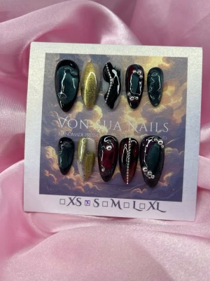Cha-Damn (S);Medium Almond - Unika handgjorda press-on naglar i svart, vinrött och guld. Naglarna har medium lång mandelform och dekoreras med silverdetaljer och swirl-mönster. S: 15 mm, 11,5 mm, 12 mm, 11 mm, 9 mm ,designen är handgjord för en edgy och glam look.
