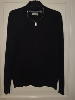 Svart halvzip-tröja från Jack & Jones - Snygg svart stickad tröja från Jack & Jones med halvzip och hög krage. Tröjan har långa ärmar och ribbade muddar vid ärmslut och nederkant. Perfekt för dig som gillar stilrena och enkla plagg med en modern touch.       Priset kan diskuteras, skriv till mig. Hämtas i Torslanda eller så fraktar jag.