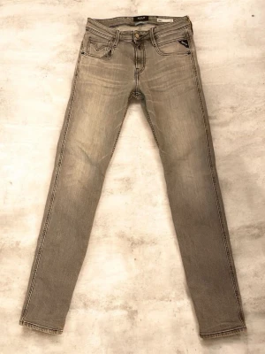 Replay anbass grå - Säljer ett par grå anbass jeans från Replay med klassisk femficksmodell och snygga kontrastsömmar. Jeansen har en diskret tvättad look och patch med Replay-logga bak i midjan. Materialet är mjukt denim som sitter tajt längs benen. 