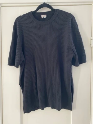 Svart ribbstickad tröja  - Svart ribbstickad tröja med rund halsringning och halvlånga ärmar. Oversized passform och mjukt material som ger en avslappnad look. Perfekt till jeans eller kjol för en enkel och stilren outfit. Använd men i fint begagnat skick   Mått Över bröstet: ca 61 cm Längd från axeln och ner: ca 67 cm  52% viskos, 28% polyester och 20% nylon  Kommer från ett djur och rökfritt hem 