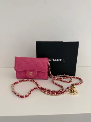 Rosa quiltad plånbok - Supersnygg rosa plånbok i quiltat läder med guldfärgad CC-logga framtill. Kedjerem i guld och rosa läderdetaljer, perfekt att bära crossbody eller runt halsen. Klassisk och trendig design med exklusiv känsla.