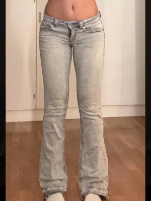 Ljusgrå bootcut jeans - Säljer ett par ljusgrå bootcut jeans med låg midja och klassiska fem fickor. Jeansen har en snygg tvättad look och utsvängda ben. Perfekta för dig som gillar en avslappnad men trendig stil.
