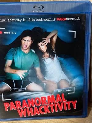 Paranormal Whacktivity Blu-ray - Blu-ray med filmen Paranormal Whacktivity, en humoristisk och sexfixerad skräckparodi. Omslaget är blått med färgstark text och bilder från filmen. Perfekt för dig som gillar komedier med övernaturliga inslag och parodier.