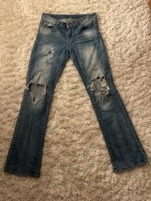 Ljusblå bootcut jeans - Säljer ett par ljusblå bootcut jeans som är lågmidjade. Dom passar bäst på en 36/S. Sköna och är lite stretchiga i både midjan och låren. 