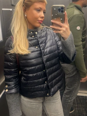 Svart pufferjacka från Herno Iconico - Säljer en svart, glansig pufferjacka från Herno Iconico. Jackan har horisontella sömmar, knappar framtill och en klassisk krage. Köpt för 5 000kr inga märken eller slitage alls. Pris kan diskuteras