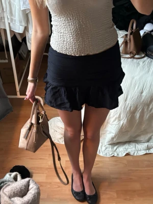 Svart volangkjol  med loose fit - Säljer en svart kjol med volangkant och loose passform. Perfekt nu till sommaren!! 