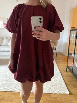 Vinröd kort klänning från ASOS DESIGN - Säljer en oanvänd vinröd kort klänning från ASOS DESIGN med lös passform och korta puffärmar. Klänningen har rund halsringning och är tillverkad i ett lätt material som ger en avslappnad look. Perfekt för dig som gillar en enkel men snygg stil.