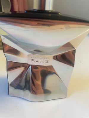 Marc Jacobs Bang parfym - Marc Jacobs Bang parfym i en unik, futuristisk flaska med silvrig, metallisk yta och geometriska former. Flaskan har en cool, krossad look och svart lock. Perfekt för dig som gillar statement-dofter och snygg design på parfymhyllan.   