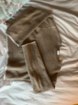 Beige stickad tröja med vita detaljer - Mysig beige stickad tröja med rund hals och långa ärmar. Den är nopprig då jag använt den🩷