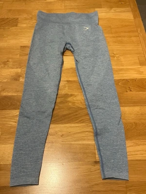 Blå sömlösa leggings från Gymshark - Snygga ljusblå sömlösa leggings från Gymshark med hög midja och diskret mönster längs benen. Tillverkade i stretchigt material som sitter skönt och formar sig efter kroppen. Perfekta för träning eller chill. Gymshark-logga framtill.
